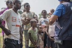 A crowd gathers to listen to WHO Community Engagement Specalist Marie-Claire Thérèse Fwelo providing information about Ebola in the city of Mbandaka.