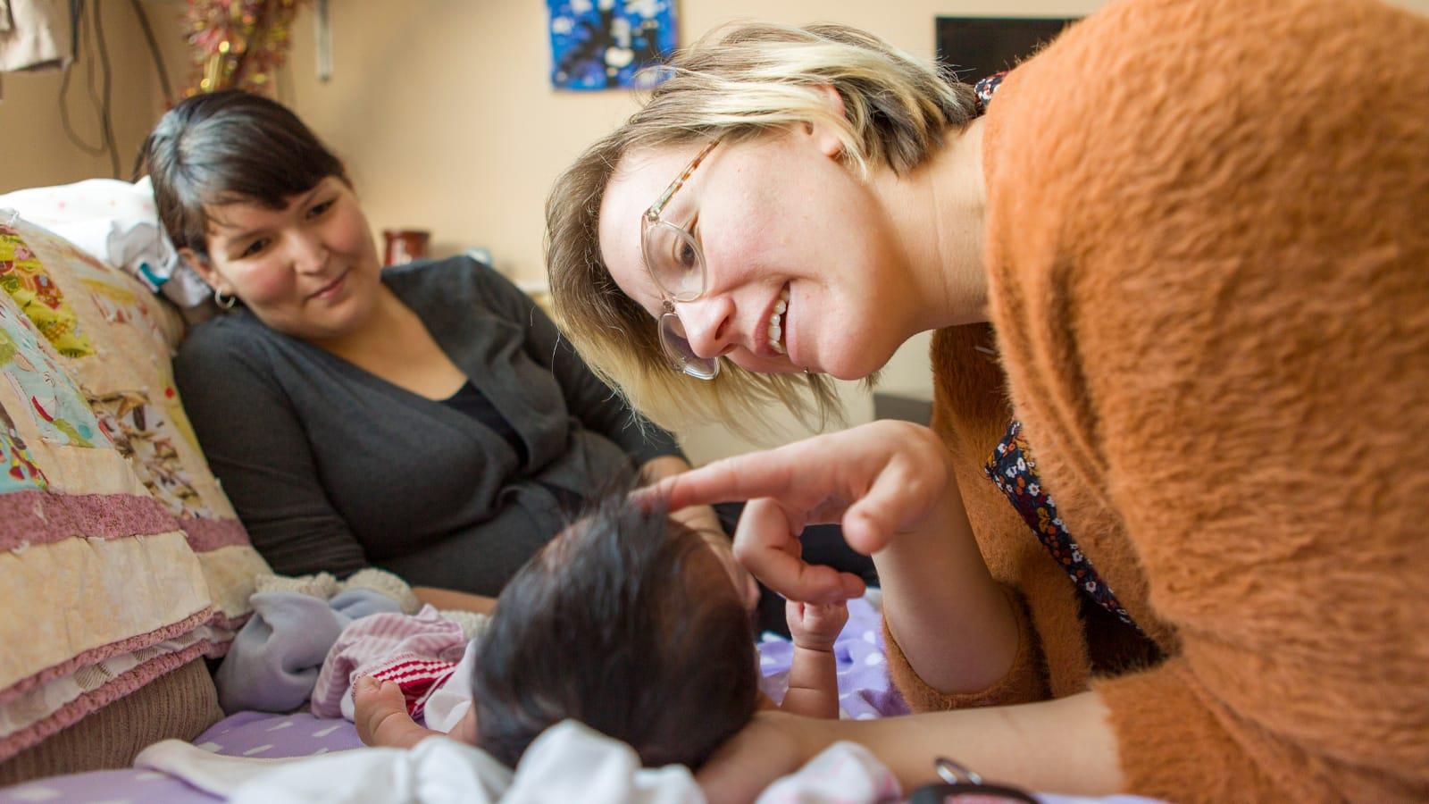 Photo 1 Photo of a midwife examining a baby as the child’s mother watches.