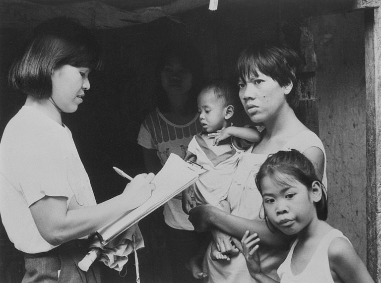 1980s A barangay health worker conducts house-to-house visit and offers health advice to mothers.