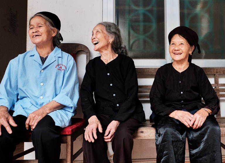 WP33470 Three older women sit on a bench laughing