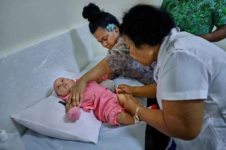 Immunization A baby is vaccinated by a nurse while her mother holds the baby's arms.